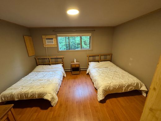 Bedroom with two double beds and a window to the forest
