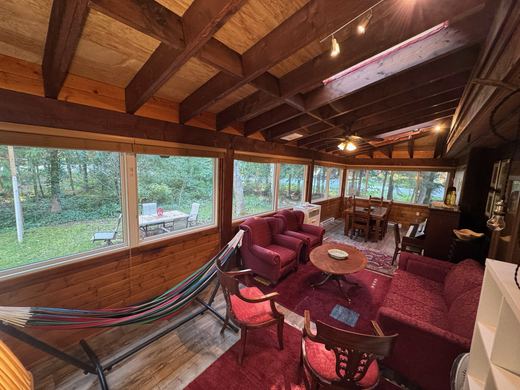 Enclosed sunroom wrapped in windows, looking out to the trees and the garden