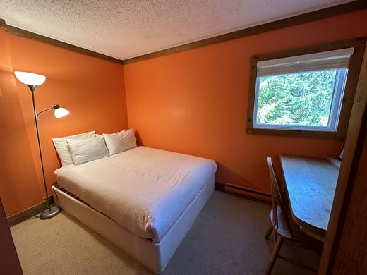 Bedroom with a bed, a desk and a window looking into the trees