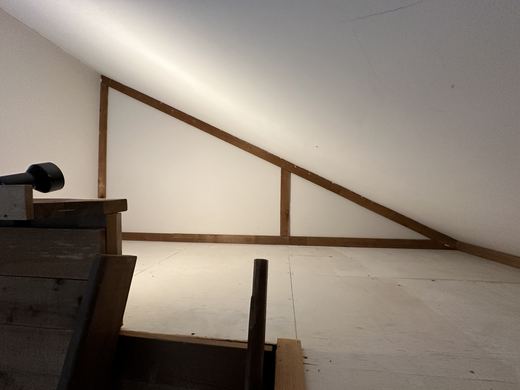 Sleeping loft under the roofline, reached by ladder from the living area