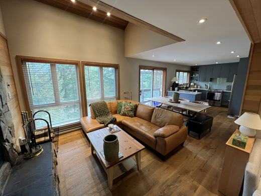 Living room at Smoketree with cedar plank walls, hardwood floors and windows to the trees